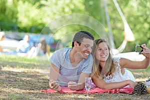 couple taking selfie on blanket in park