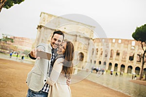 Couple taking selfie in front of Colosseum in Rome, Italy