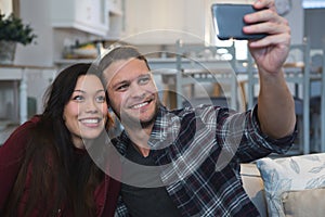 Couple taking selfie with mobile phone in living room