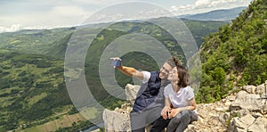 Couple taking a selfie at mountain viewpoint