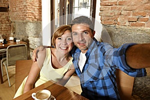 Couple taking selfie photo with mobile phone at coffee shop smiling happy in romance love concept