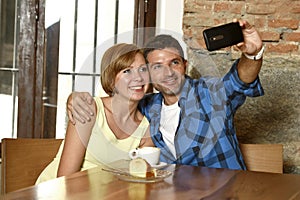 Couple taking selfie photo with mobile phone at coffee shop smiling happy in romance love concept