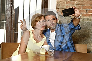 Couple taking selfie photo with mobile phone at coffee shop smiling happy in romance love concept