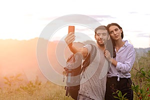 Couple taking selfie photo with smart phone hiking on mountain