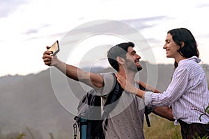 Couple taking selfie photo with smart phone hiking on mountain