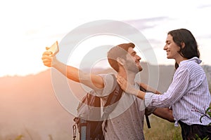 Couple taking selfie photo with smart phone hiking on mountain