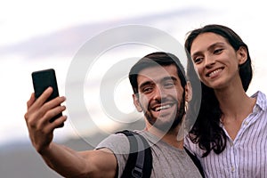 Couple taking selfie photo with smart phone hiking on mountain