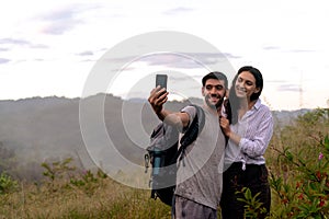 Couple taking selfie photo with smart phone hiking on mountain