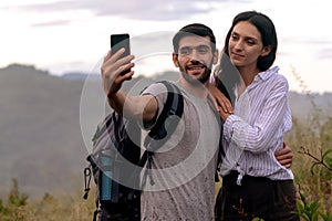 Couple taking selfie photo with smart phone hiking on mountain