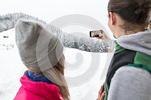 Couple Taking Selfie Photo On Smart Phone Snowy Village Wooden Country House Man Woman Winter Snow