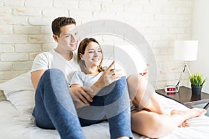 Couple Taking Selfportrait On Tablet Computer On Bed