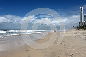 Couple talk on stormy beach with buildings of Gold Coast - Surfers Paradise Queensland Australia behind them