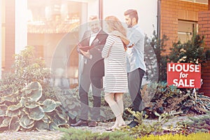 Couple talking with consultant during transaction of buying house