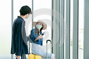 Couple talking at international airport making selfie with mobile phone and waiting for her flight at departure terminal