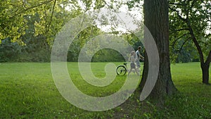 A couple on a tandem bike rides through the park between the trees