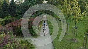 A couple on a tandem bike rides through the park between the trees