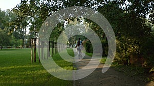 A couple on a tandem bike rides through the park between the trees