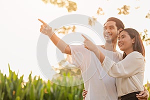 couple teen standing happy smiling together park outdoors sun shining hand pointing high for life planning future insurance