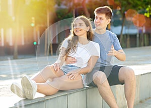 A couple of teenagers is sitting in the park