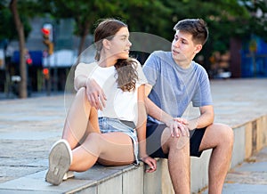 A couple of teenagers is sitting on the step