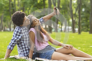 Couple of teenagers taking selfie on picnic outdoors