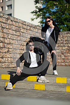 A couple of teenagers on a walk with a boombox.Beautiful girl in a black tracksuit