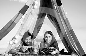 Couple in a tent. Camping lovers. Romantic couple eating watermelon and corn.