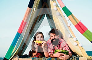 Couple in a tent. Romantic couple have breakfast on holiday, eating watermelon and corn.