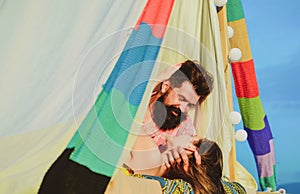 Couple in a tent. Young couple in love spends time together and camping. Man embracing and going to kiss sensual woman.
