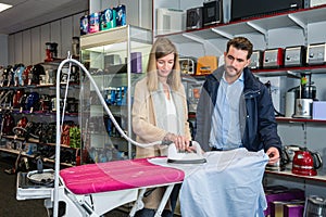 Couple Testing Iron By Ironing Shirt In Hypermarket photo