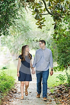 A couple in their forties who are parents are taking a walk in the neighborhood on the sidewalk outside in the summer