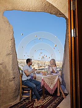 A couple and their romantic breakfast in Cappadocia on the amazing background of flying balloons