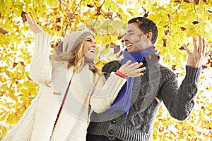 Couple Throwing Leaves In Autumn Garden