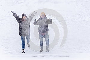 Couple throwing snow and enjoying winter in field, full of snow