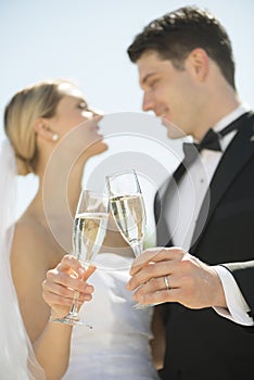 Couple Toasting Champagne Flutes Against Sky