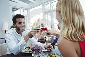 Couple toasting glasses of wine while having meal