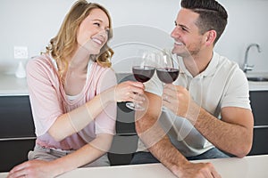 Couple toasting red wine glasses at table