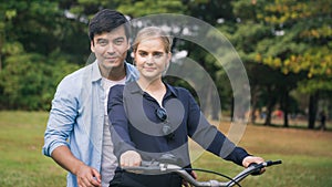 Couple together enjoying romantic walk with bicycle in park
