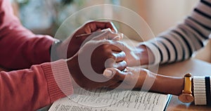 Couple, together and holding hands with bible in home for worship, prayer or peace for bond in closeup. Man, woman and