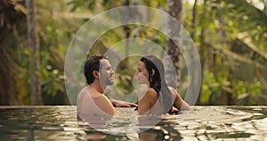 Couple Together Relaxation and Spending Time in Infinity Swimming Pool Outdoors During Tropical Vacation