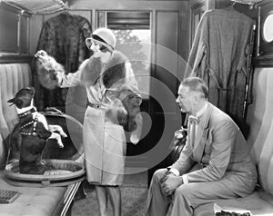 Couple together in a train and feeding a dog