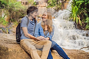 Couple of tourists with a backpack on the background of a waterfall