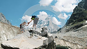 Couple of tourists with backpacks in the trek climb to the top of the stone and kiss.