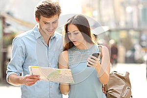 Couple of tourists consulting a city guide and mobile gps