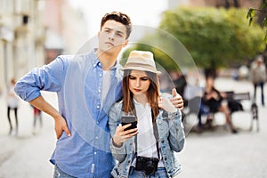 Couple of tourists consulting smartphone gps in the street searching locations in new city