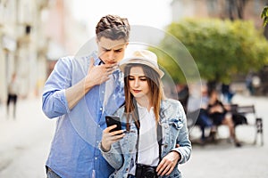 Couple of tourists consulting smartphone gps in the street searching locations in new city