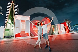 Couple tourists hugging and enjoys their journey near the caption I love Dubai at night. Sightseeing attractions in UAE