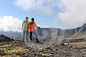 Couple of tourists are on the plateau embracing and looking at t