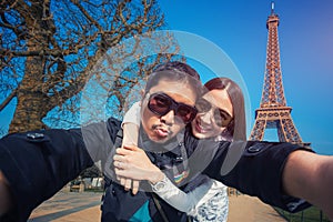 Couple Tourists selfie with mobile phone near the Eiffel tower in Paris, France