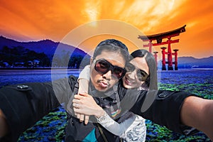 Couple Tourists selfie with mobile phone near the Tori gate in hiroshima, Japan